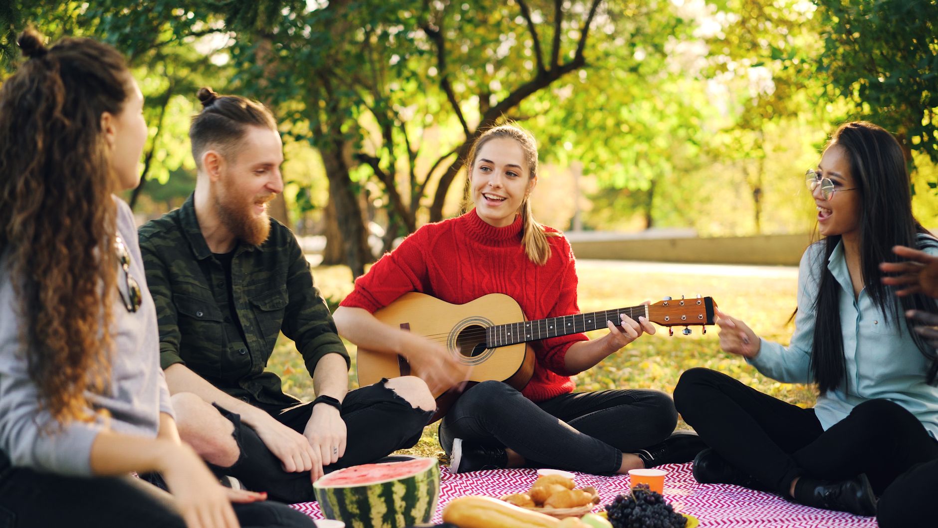 Les copains d'abord » de — guitariste chantant en plein air avec amis